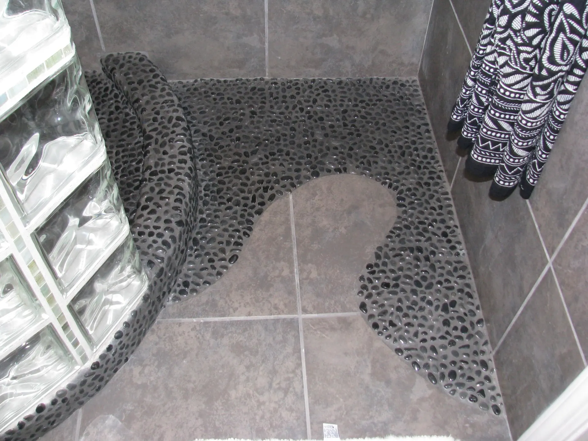 River rock pebble mosaic shower floor meeting tile flooring in a custom bathroom